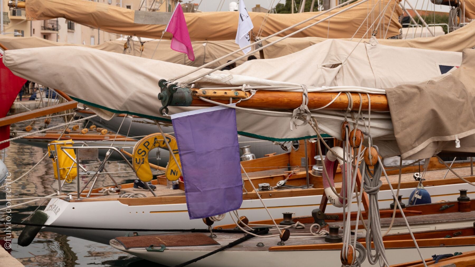 Gréements, housses et pavillons d’un voilier classique au port.