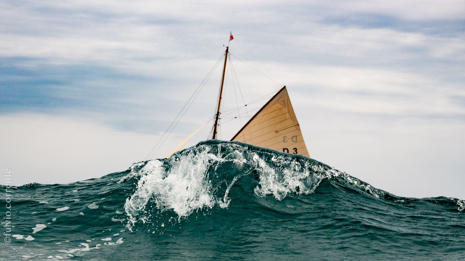 Voile beige dépassant d’une vague qui déferle.
