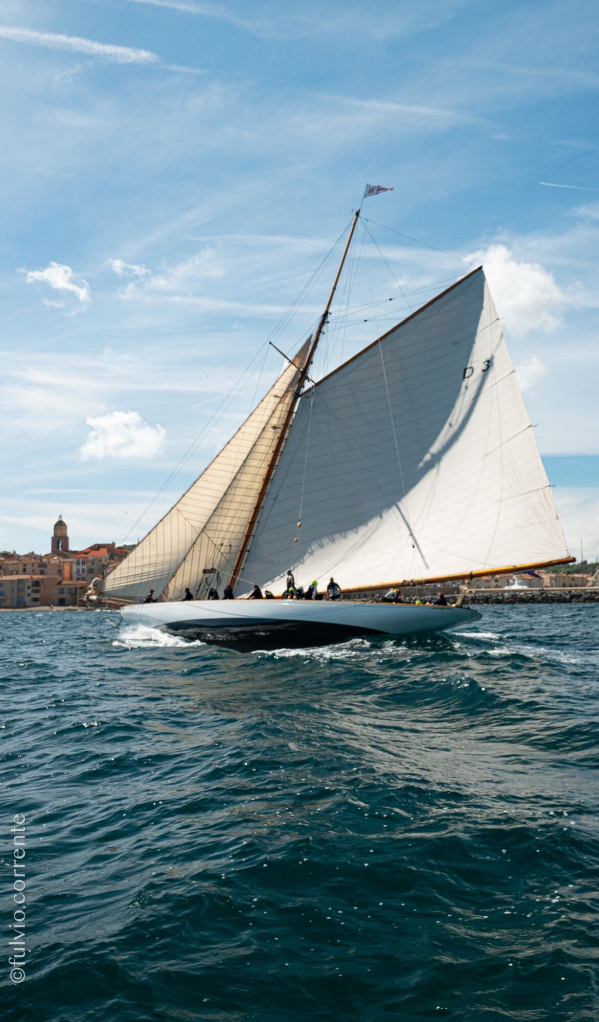 Voilier à voile blanche sur une mer agitée devant Saint-Tropez.