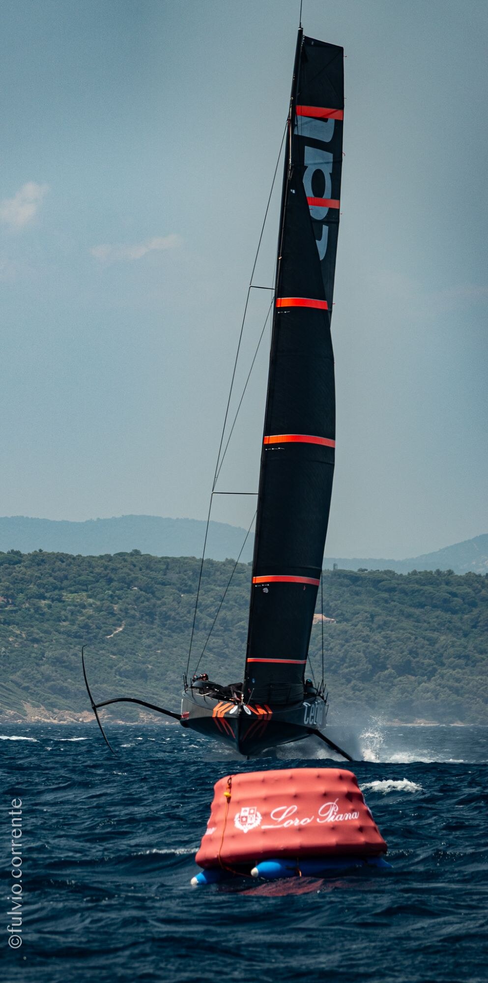Voile noire dressée au-dessus d’une bouée gonflable rouge de parcours.