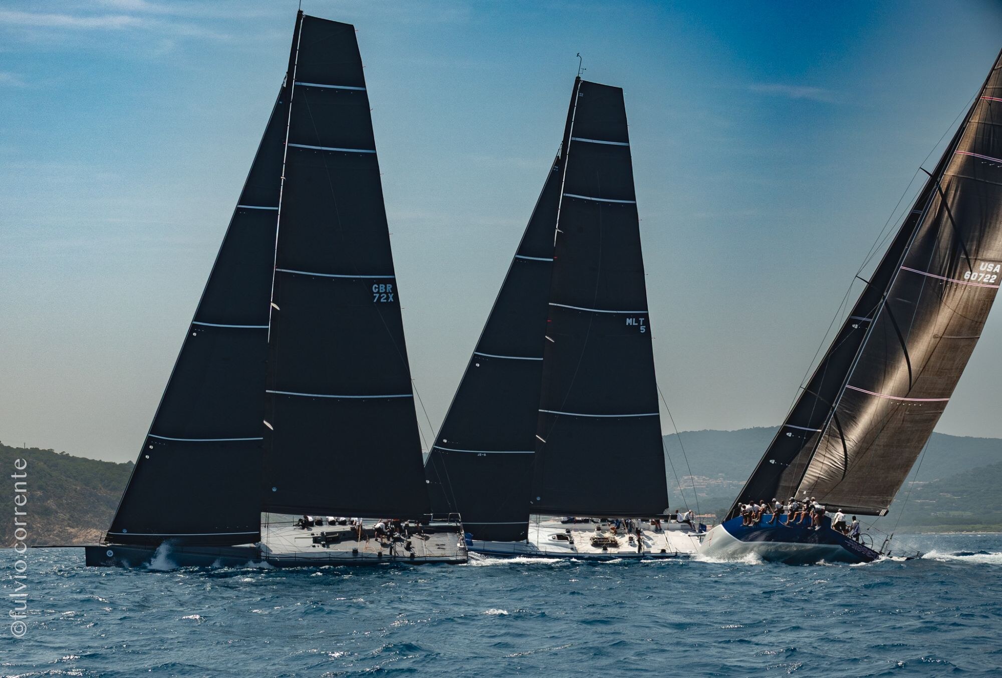 Trois voiliers de course aux voiles noires côte à côte.