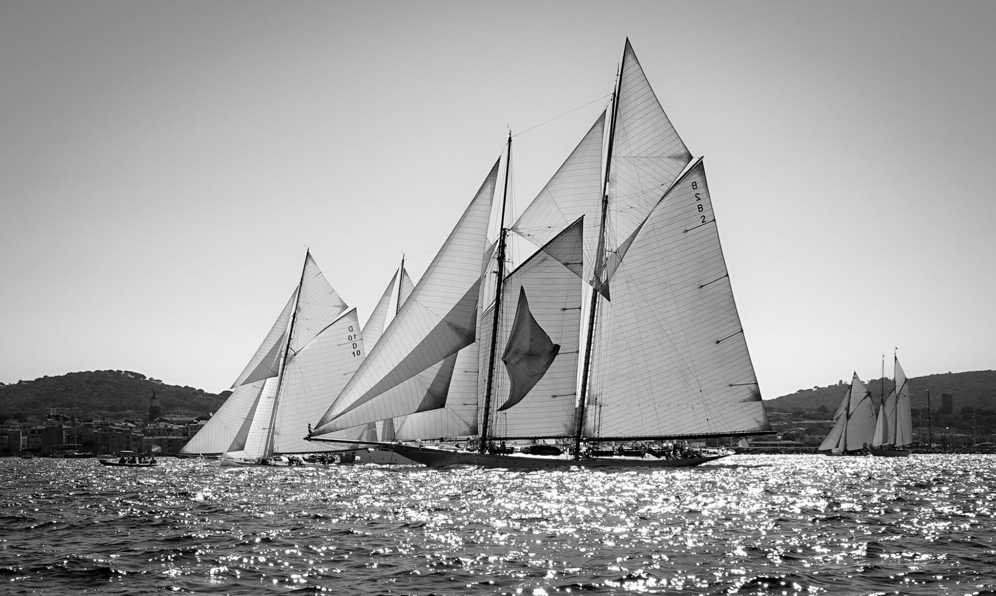 Voiliers classiques naviguant côte à côte, photographie en noir et blanc.