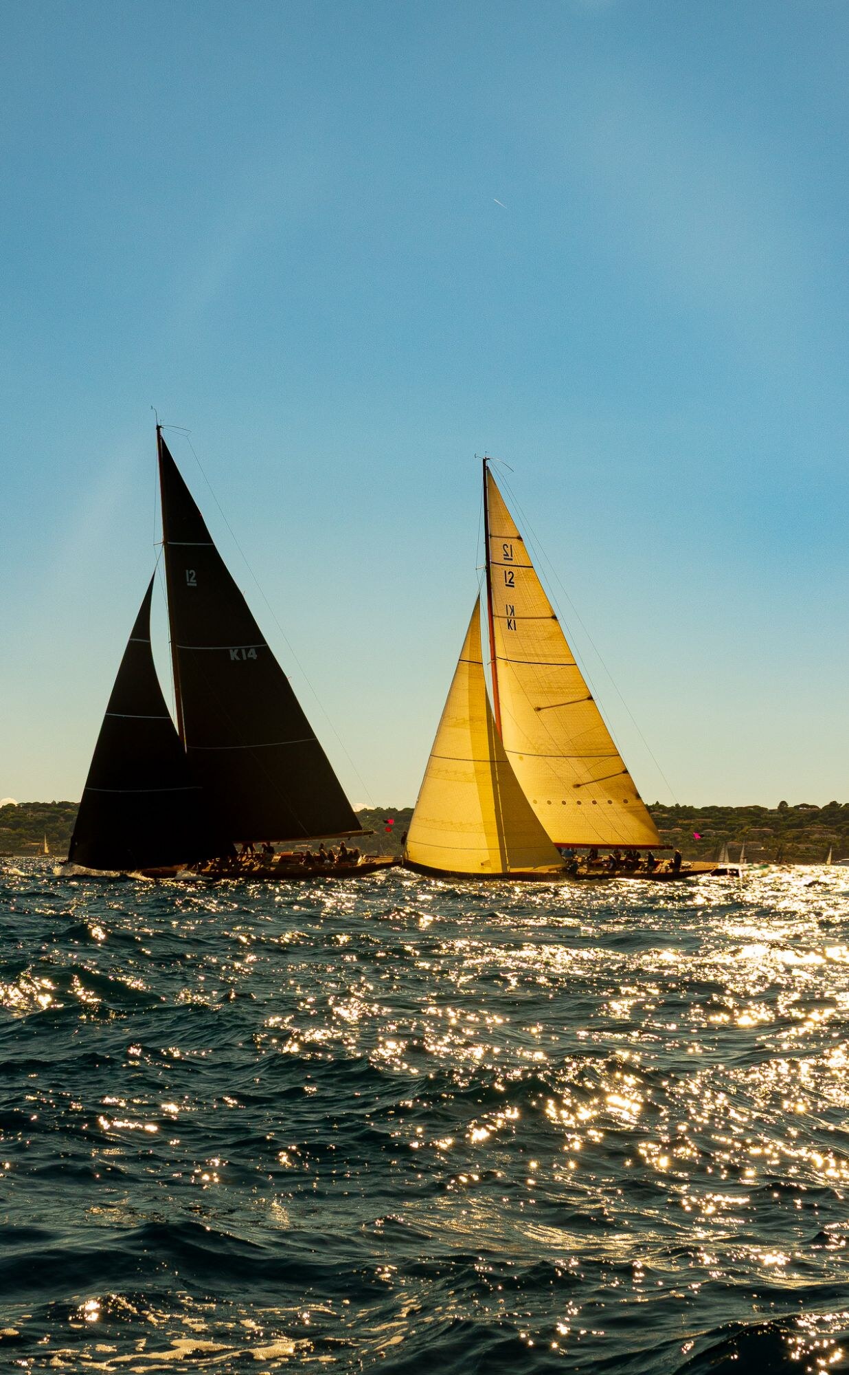 Deux voiliers, l’un aux voiles noires, l’autre aux voiles jaunes, sur une mer dorée.