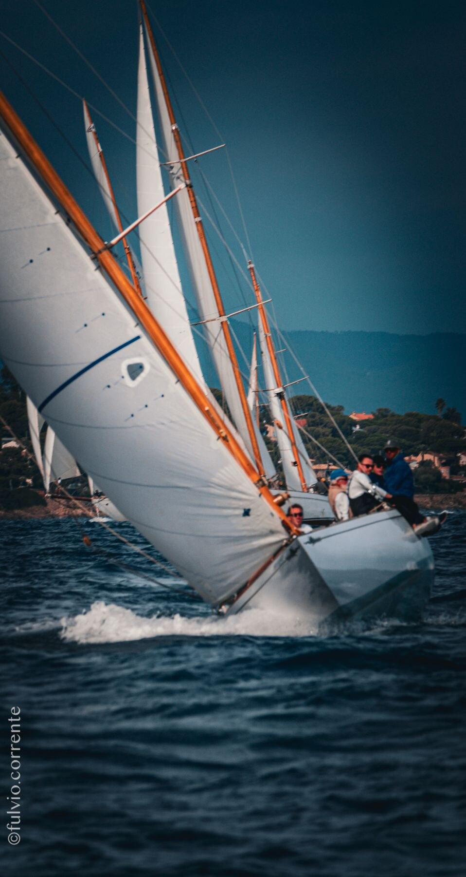 Voilier gîté sur une mer sombre, voiles blanches dans une lumière froide.