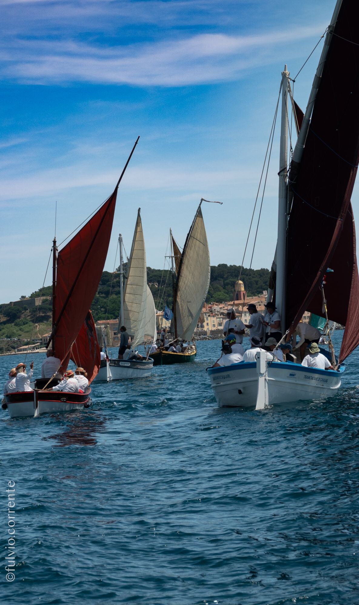 Barques à voiles latines brunes et blanches sous un ciel bleu.