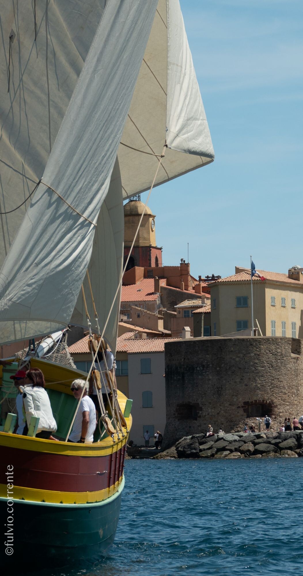 Barque à coque verte et jaune longeant la tour du port de Saint-Tropez.