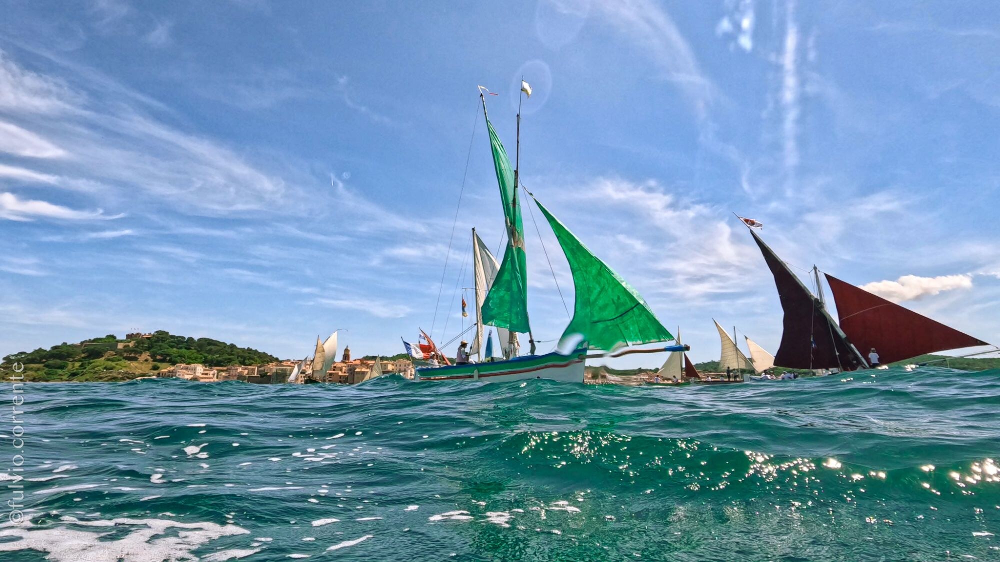 Barques à voiles vertes et brunes vues à fleur d’eau, ciel de traîne.