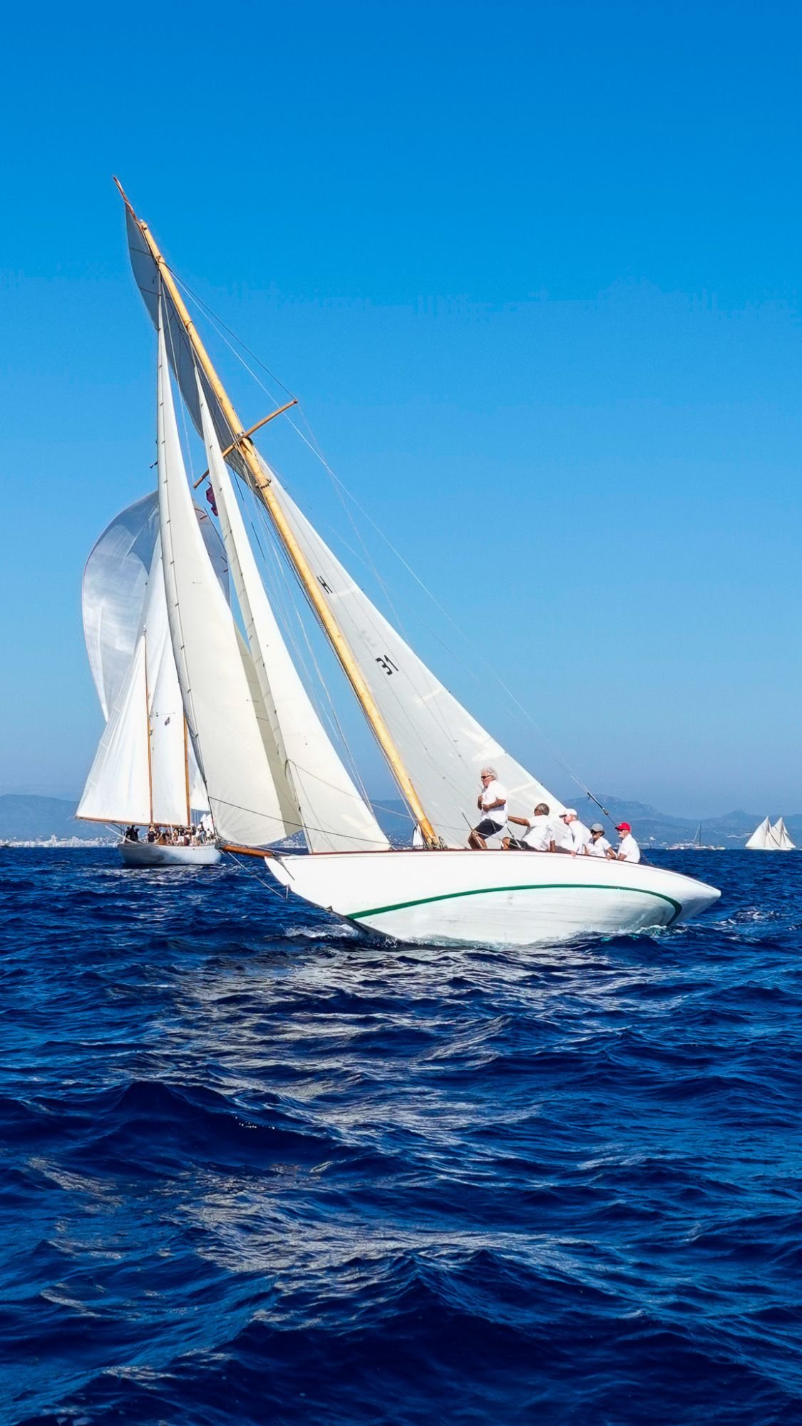 Voilier classique blanc naviguant sous voiles par mer bleue.