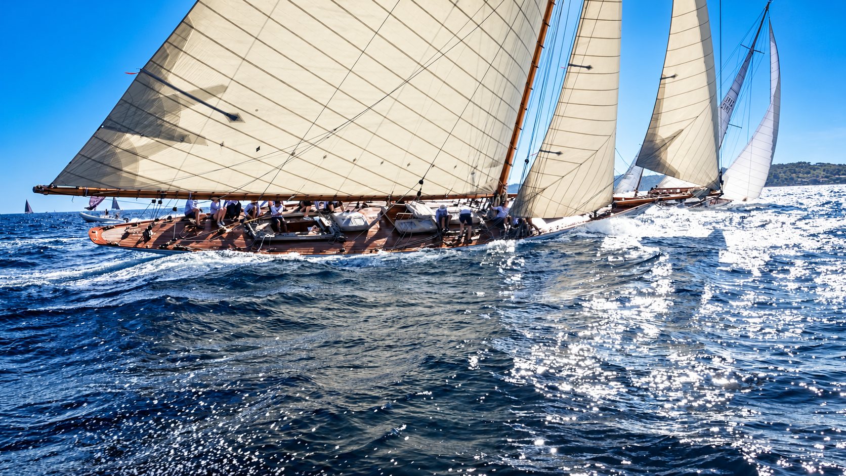 Voiliers classiques en régate sur une mer bleue ensoleillée.